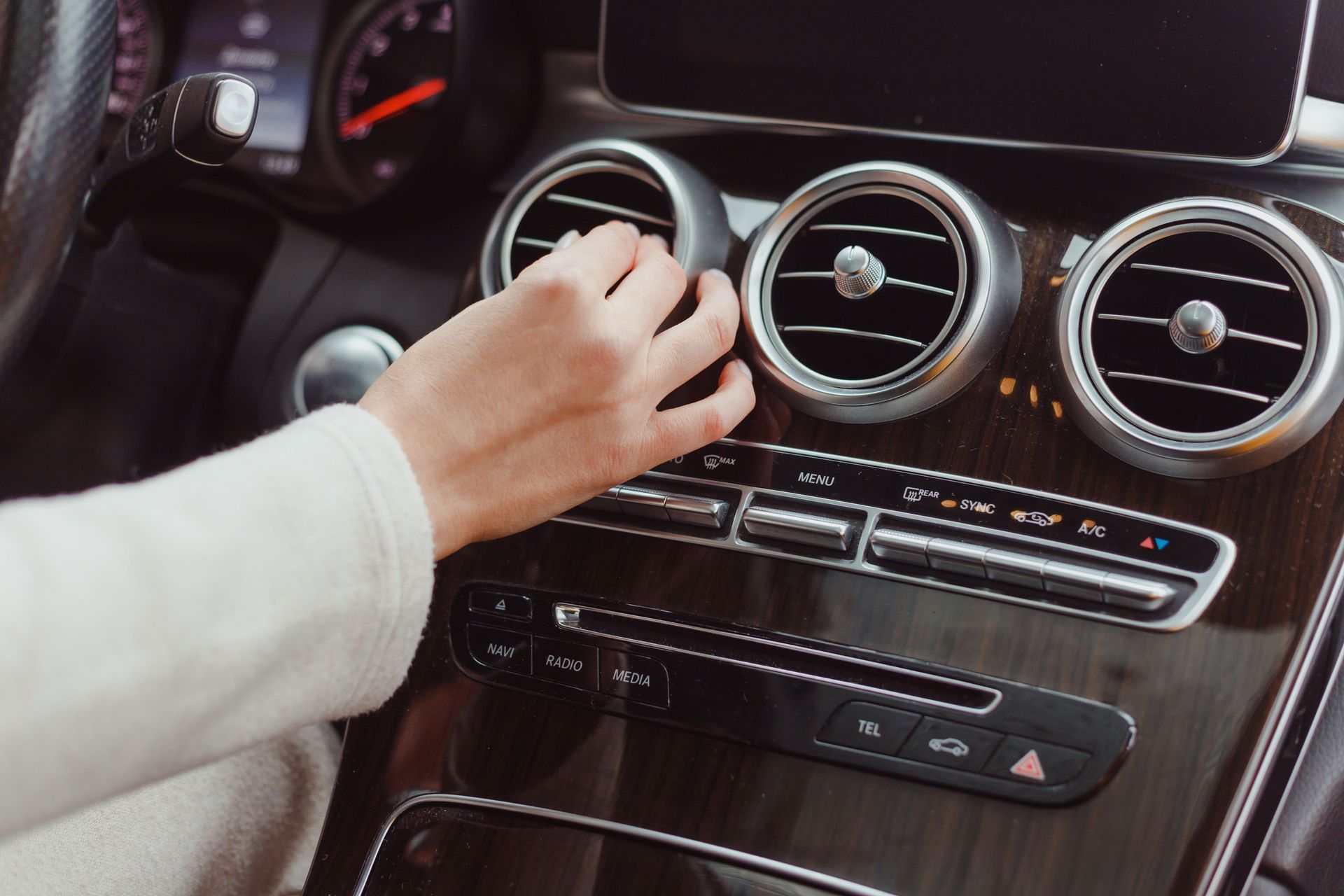 A woman is adjusting the air conditioning in her car