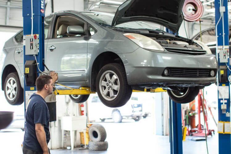 A man is looking at a car on a lift in a garage