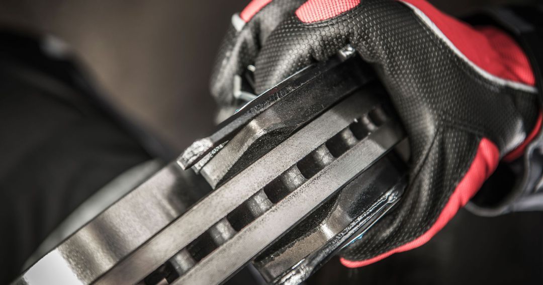 A person wearing red and black gloves is holding a brake disc.