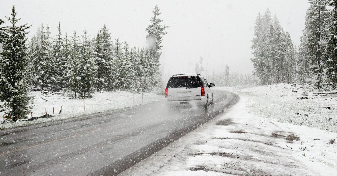 A white suv is driving down a snowy road