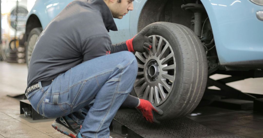 A man is changing a tire on a car in a garage.