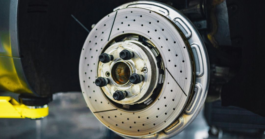 A close up of a brake disc on a car on a lift.