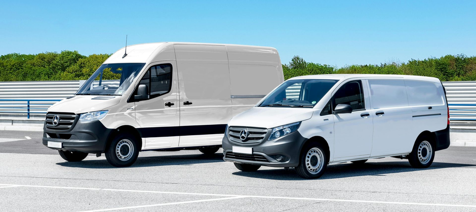 Two white delivery vans parked on a sunny waterfront road under a clear blue sky