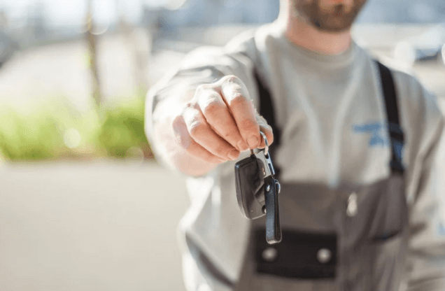 A man is holding a car key in his hand.