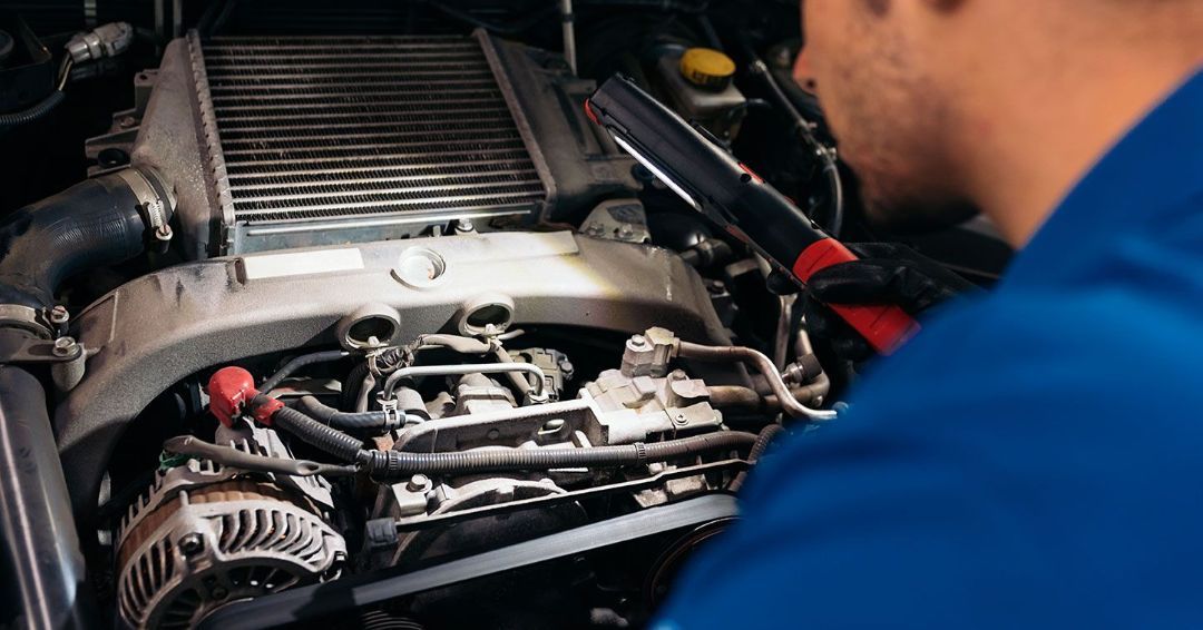A man in a blue shirt is working on a car engine