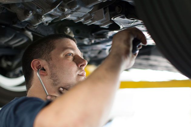 A man is working under a car with a wrench.