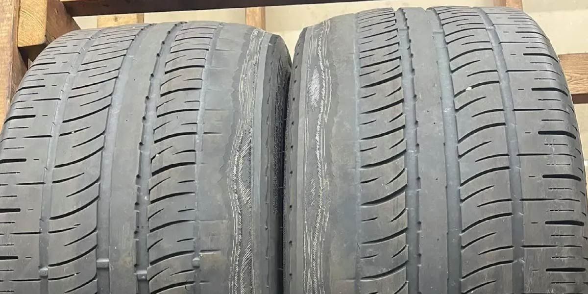 Two used tires stacked together, showing tread wear on the inner wall do to bad stock tesla camber