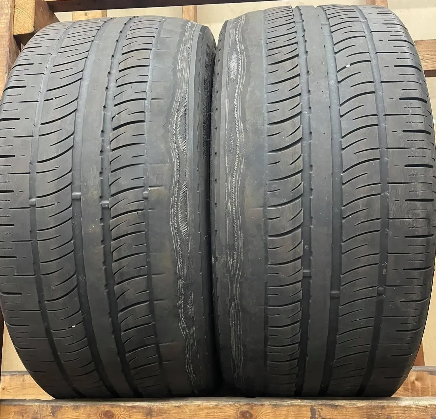 Two used tires stacked together, showing tread wear on the inner wall do to bad stock tesla camber