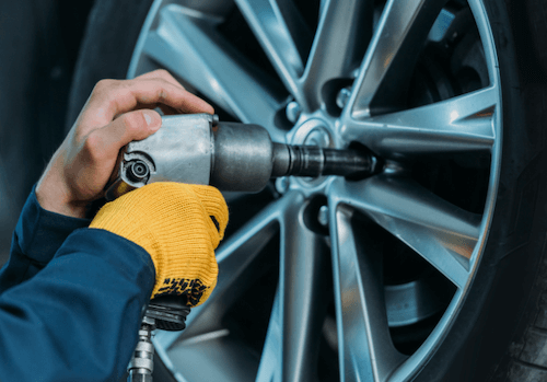 A man is working on a car wheel with a wrench.