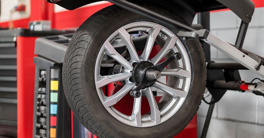 A car wheel is being balanced on a machine in a garage.