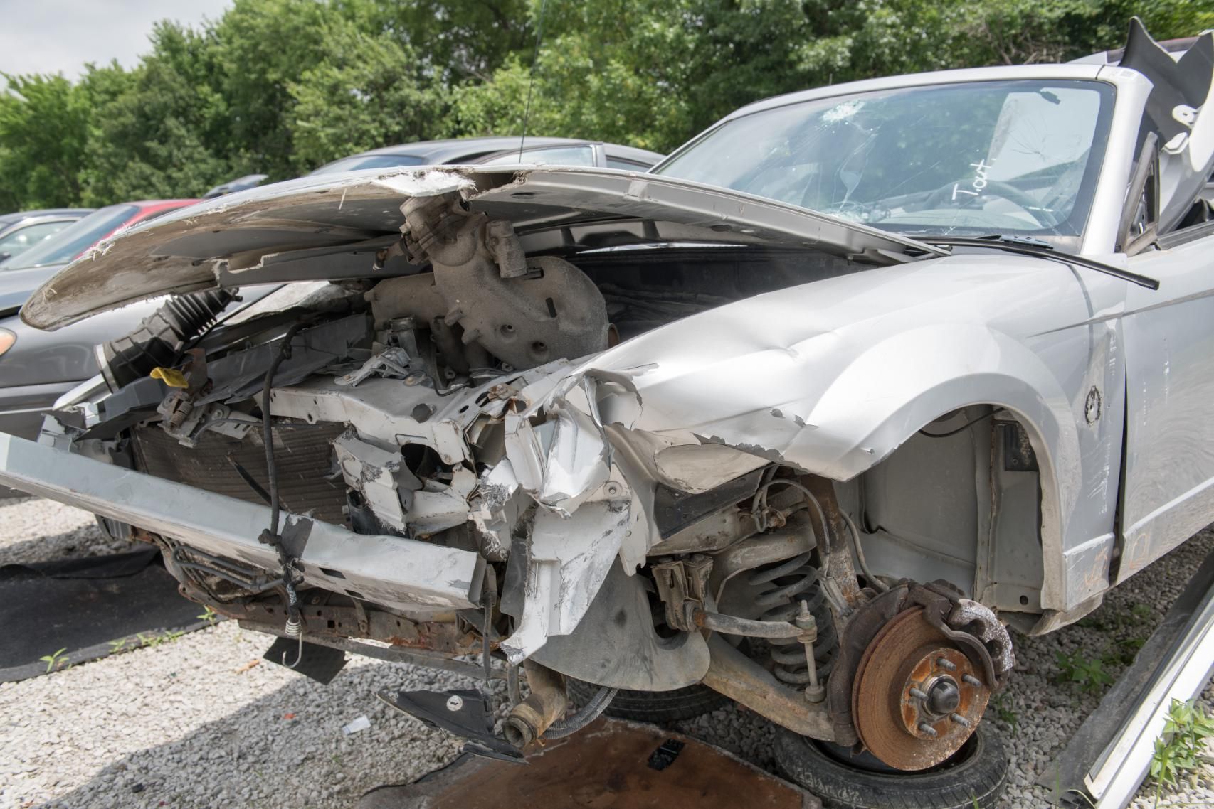A car that has been damaged in a car accident is sitting in a parking lot.