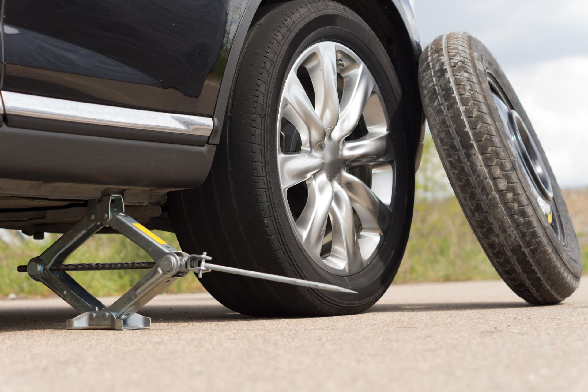 A car is sitting on a jack with a tire on it.