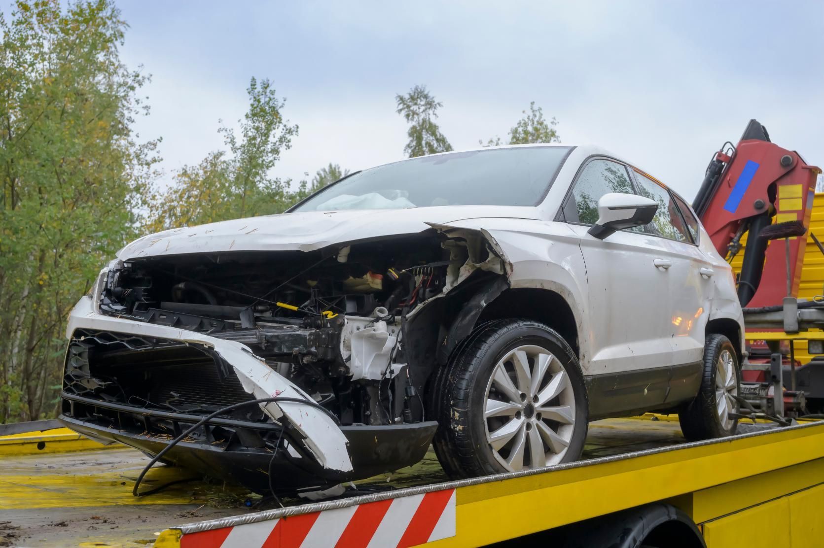 A damaged car is being towed by a tow truck.