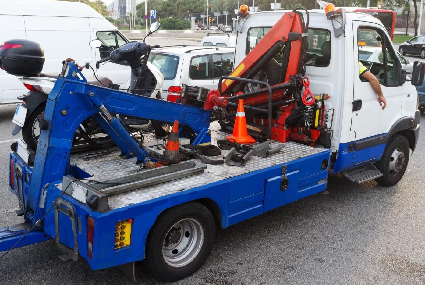 A blue and white tow truck with a motorcycle on the back.