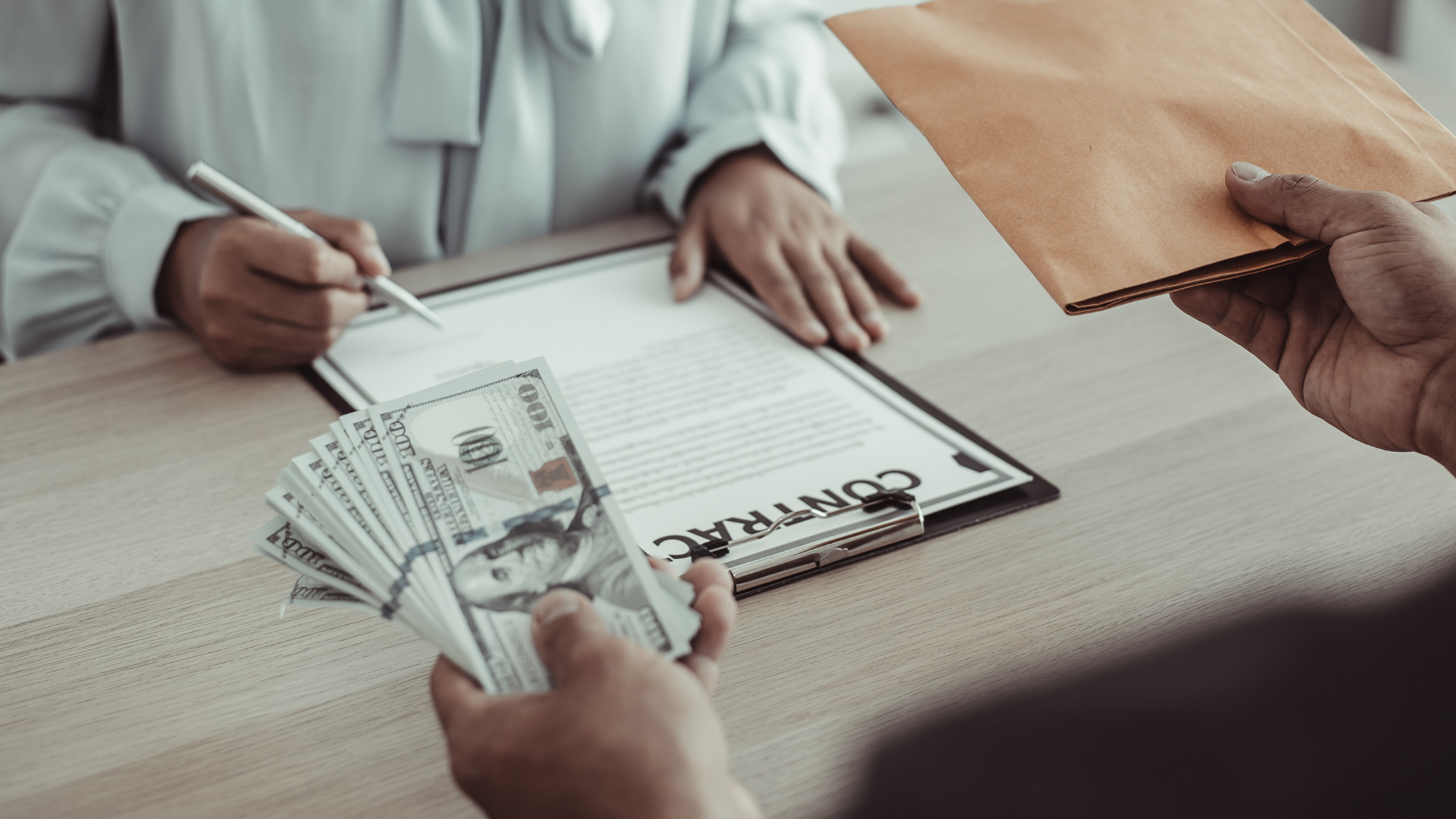A man is handing a stack of money to a woman who is signing a contract.