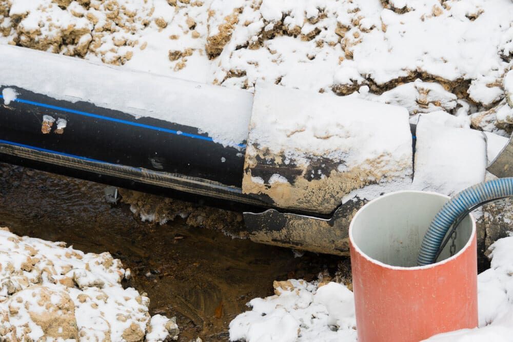 A Red Pipe Is Sitting In The Snow Next To A Black Pipe — Chad Taylor Plumbing In Forster, NSW