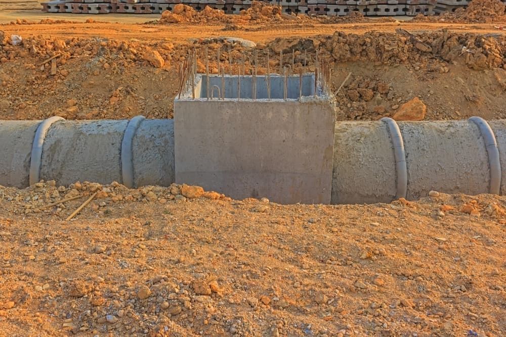 A Concrete Pipe Is Being Installed In The Dirt — Chad Taylor Plumbing In Forster, NSW