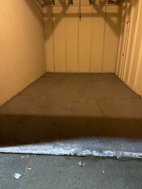An empty garage with a concrete floor and a white wall.