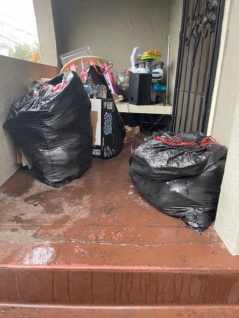 A bunch of trash bags are sitting on the steps of a house.