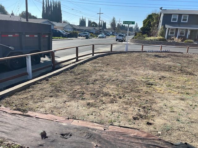 A truck is parked on the side of the road next to a fence.