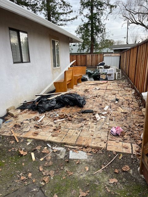 The backyard of a house with a lot of trash on the ground.