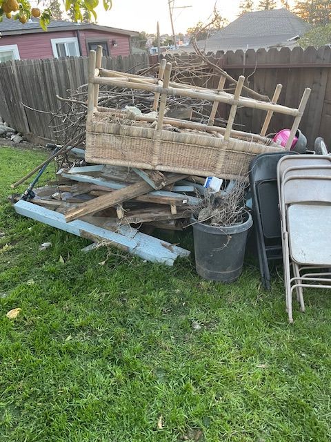 A pile of wood and chairs is sitting on top of a lush green field.