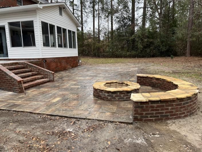 Brick patio with fire pit and seating area, next to a sunroom and stairs.