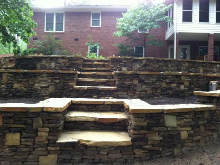 Stone steps and retaining walls in front of a brick building.