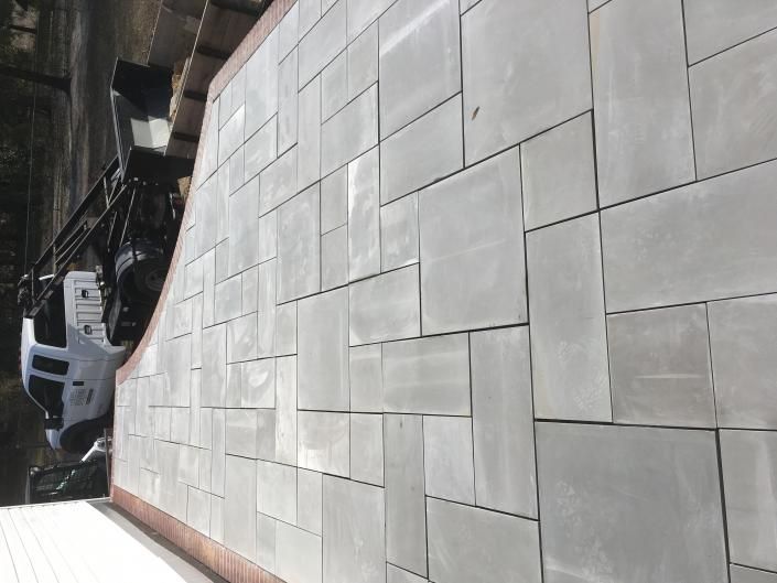 Gray stone wall with a curved edge and irregular rectangular tile pattern.
