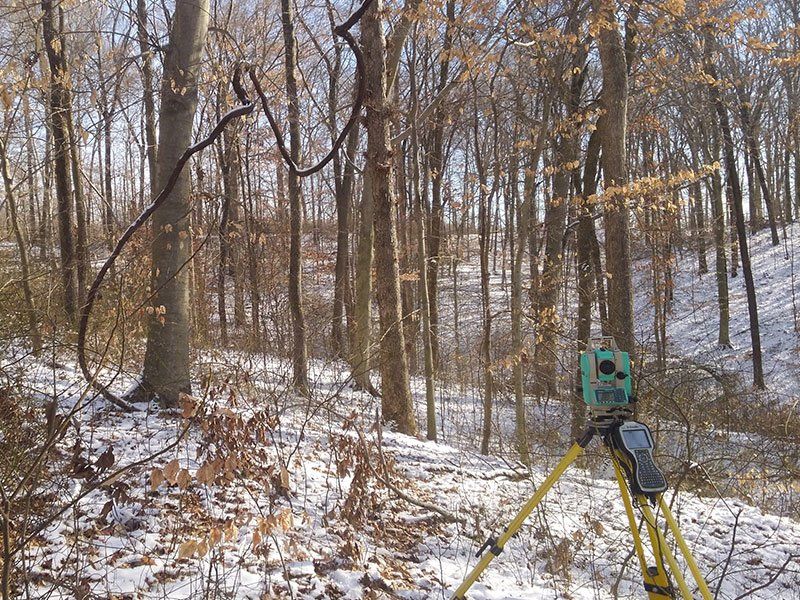 Surveyor Tripod Measures Property Boundary — Jasper, IN — Brosmer Land Surveying & Engineering Inc.
