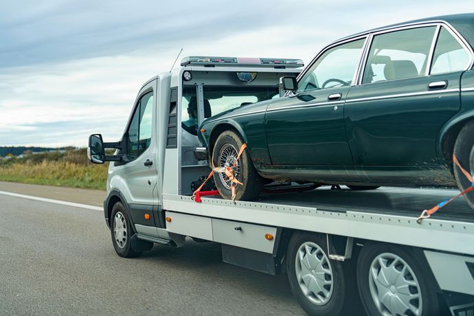 A tow truck is towing a car on the side of the road.