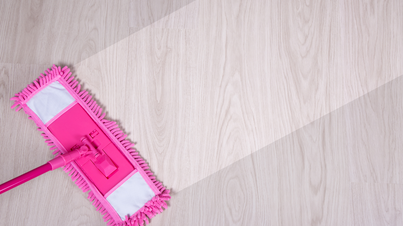 a pink mop is cleaning a wooden floor .