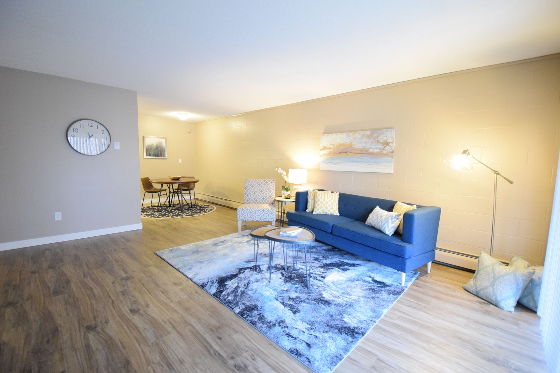 A living room with a blue couch , chair , table and rug.