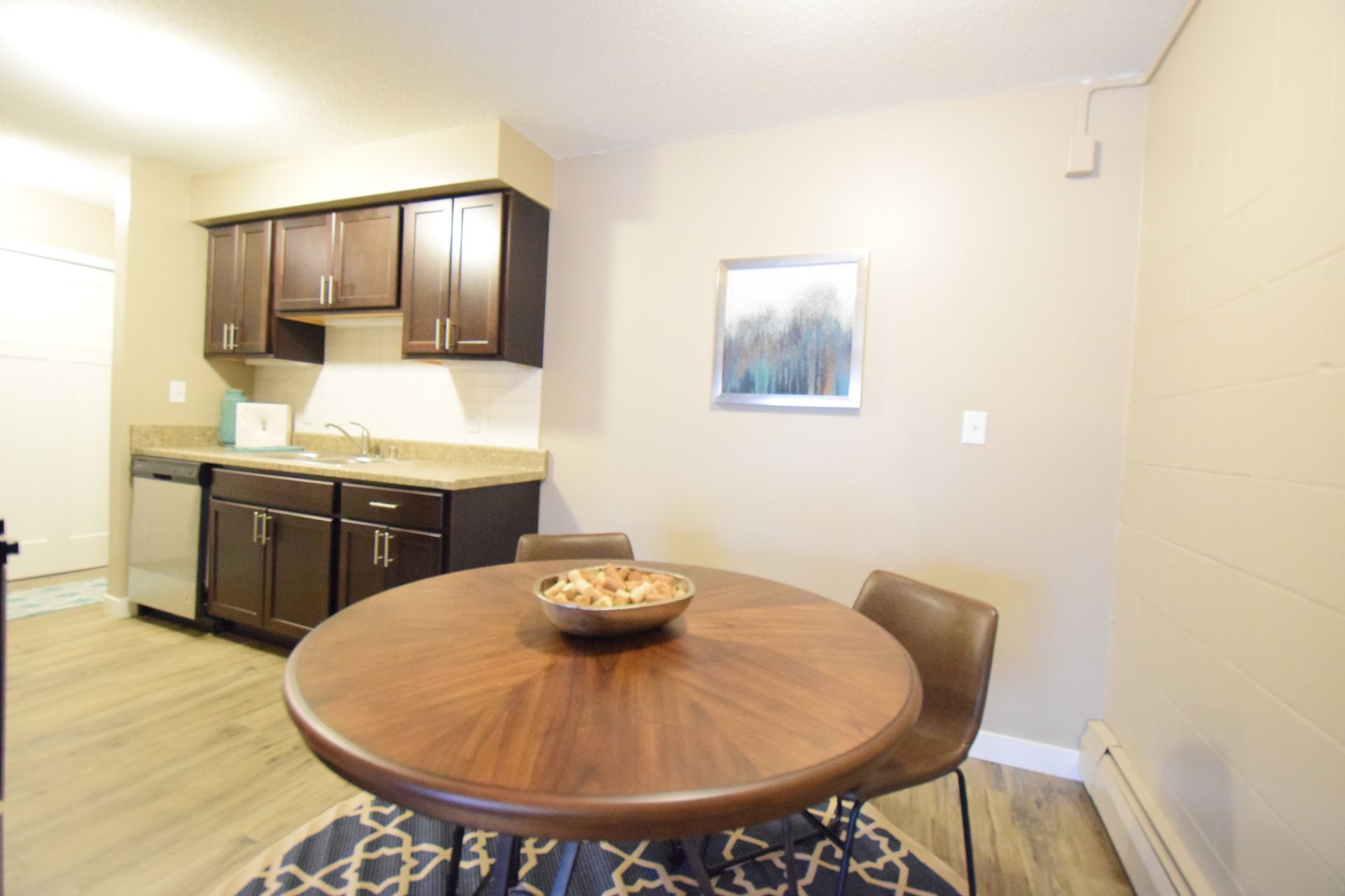 A kitchen with a round table and chairs and a bowl of food on it.