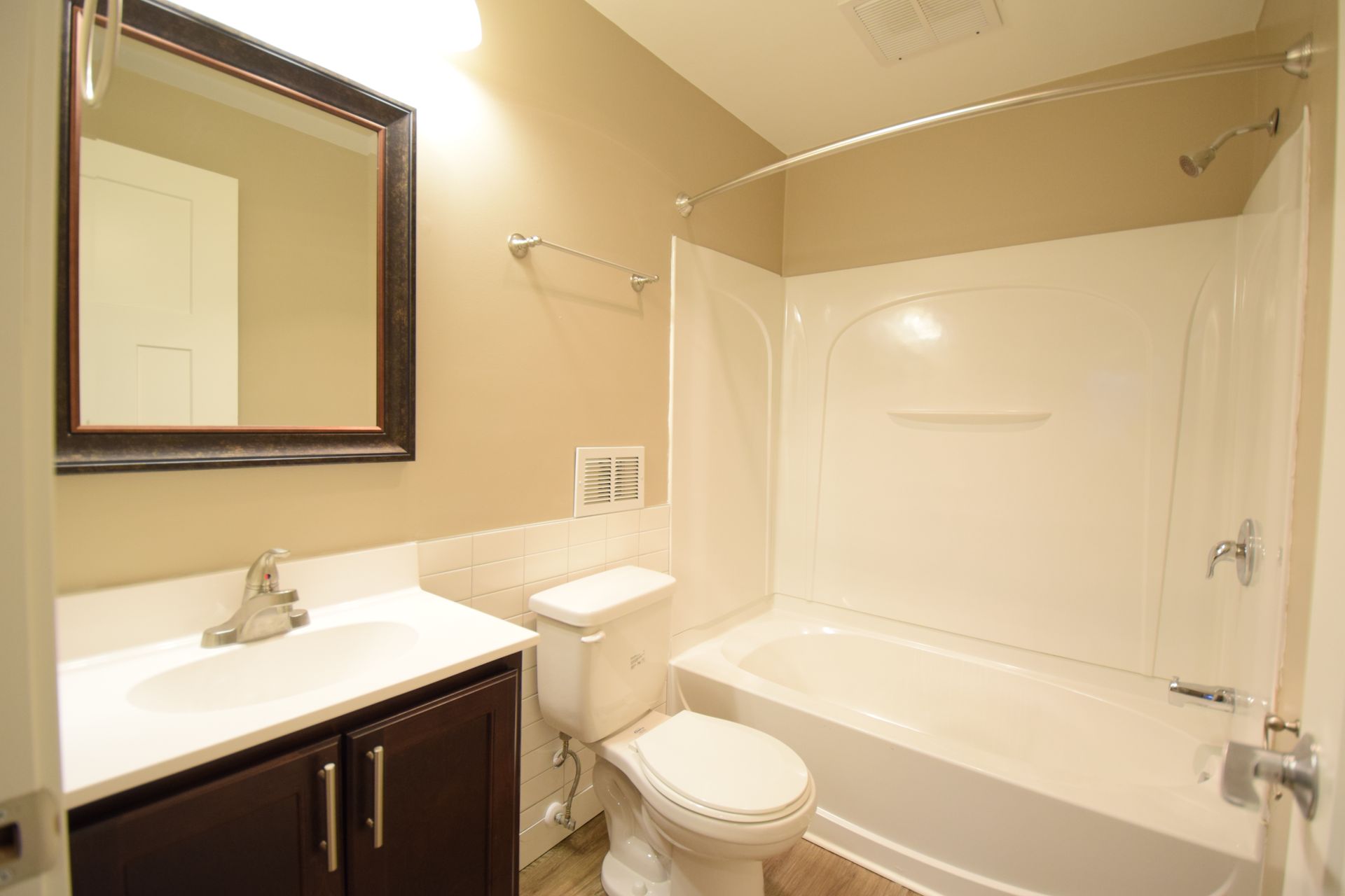 A bathroom with a toilet , sink , bathtub and mirror.