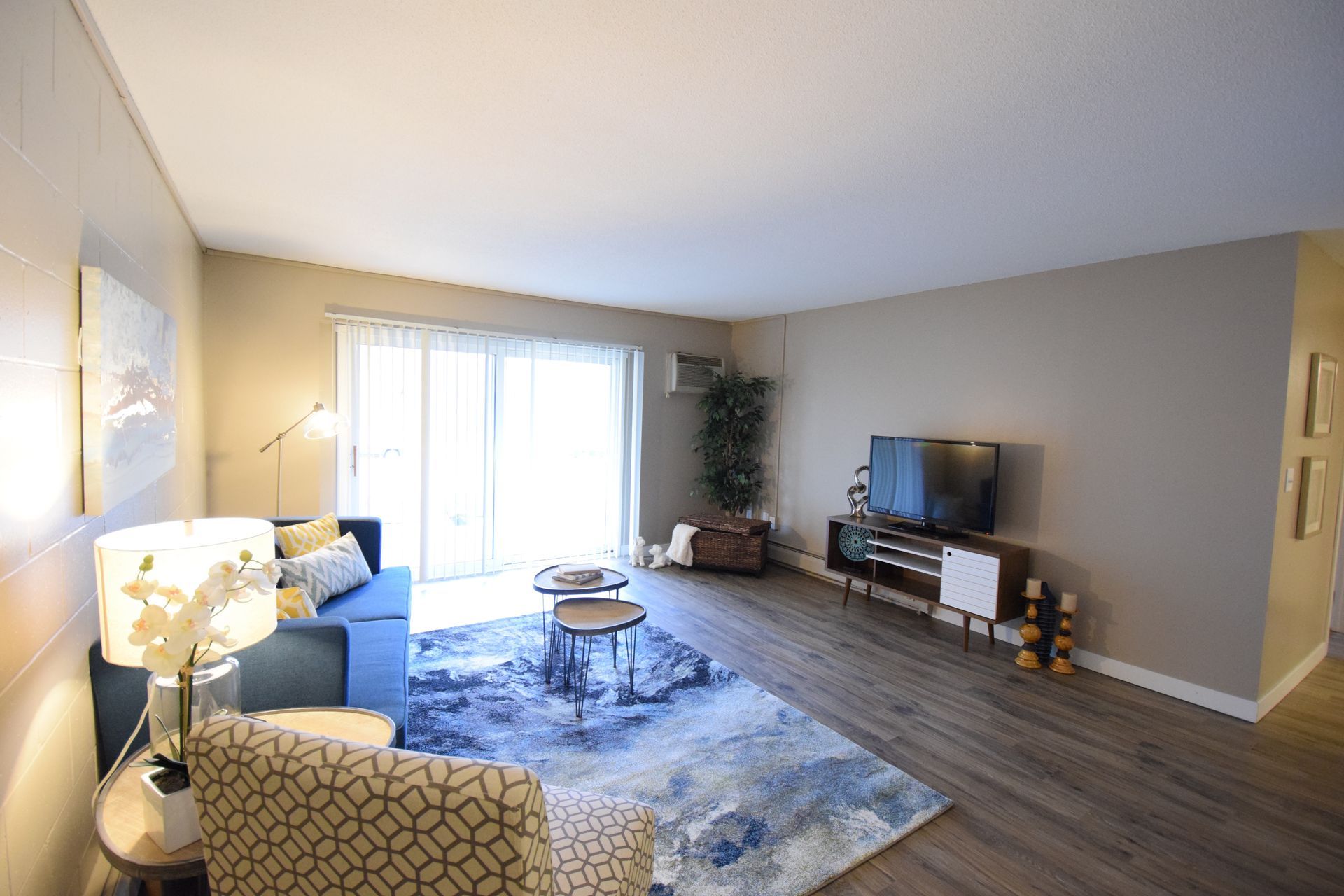 A living room with a couch , chair , television and sliding glass doors.