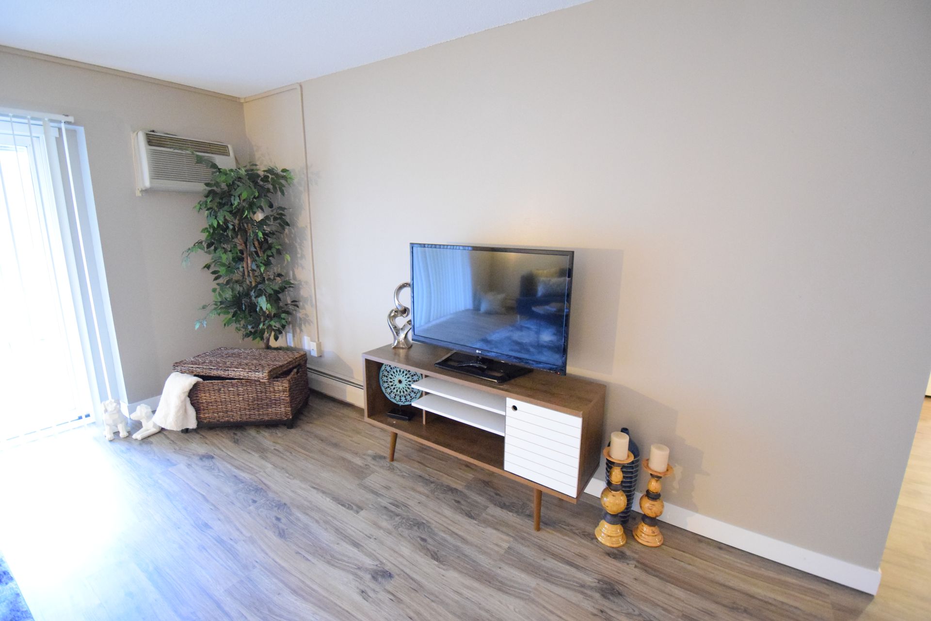 A living room with a flat screen tv on a wooden entertainment center.