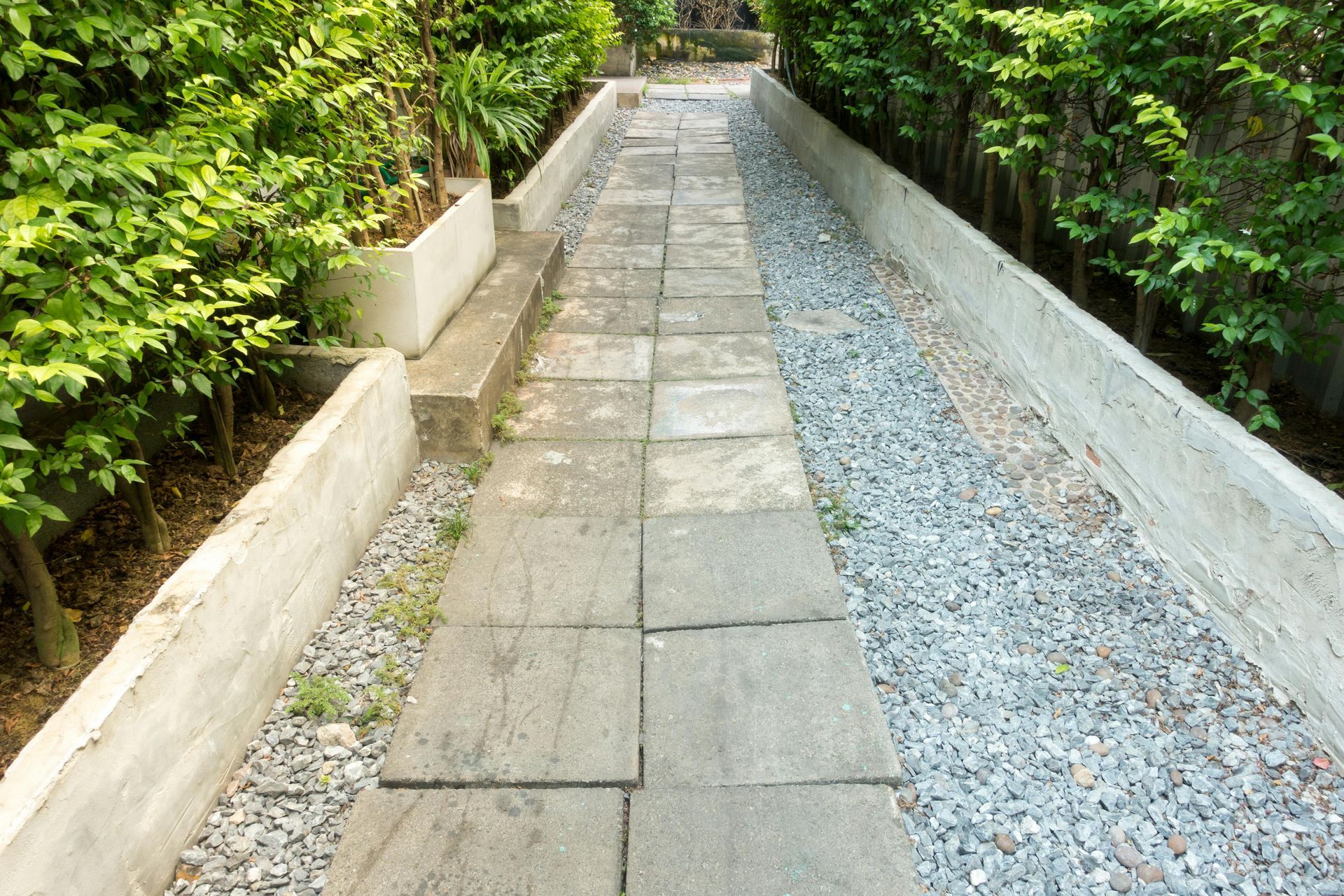 Stone path flanked by gravel and greenery, leading uphill.