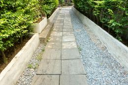 Stone path flanked by gravel and greenery, leading uphill.