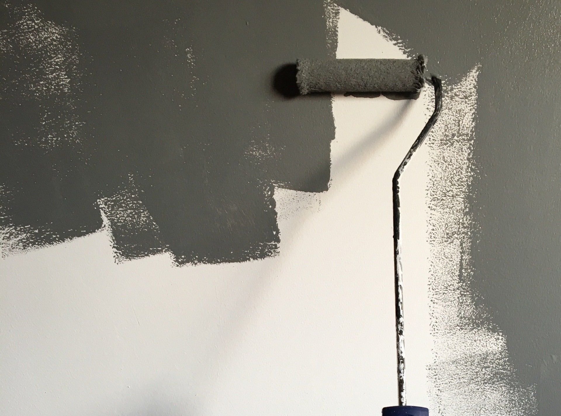 A paint roller is being used to paint a wall