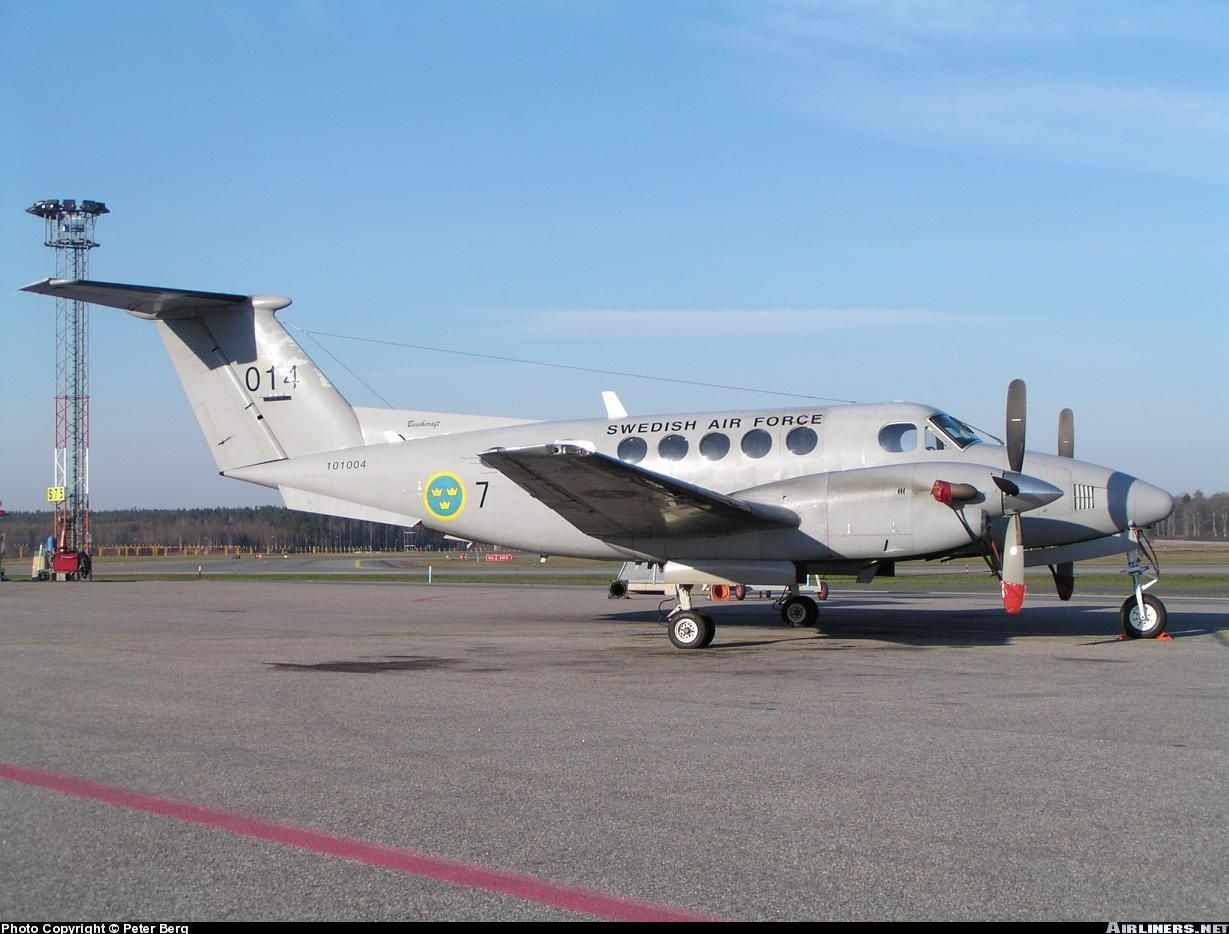 Ett grått Beechcraft King Air-flygplan parkerat på ett flygfält, med orden 