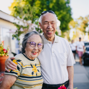 A man and a woman are posing for a picture on a sidewalk.
