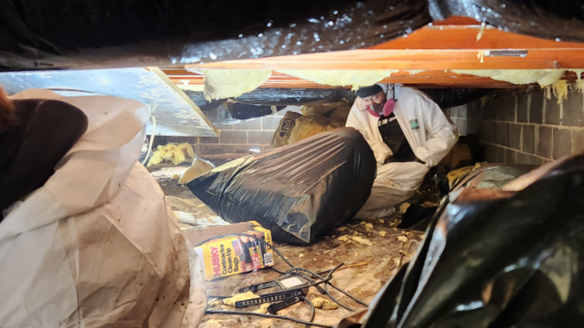 A man is working under a ceiling in a basement.