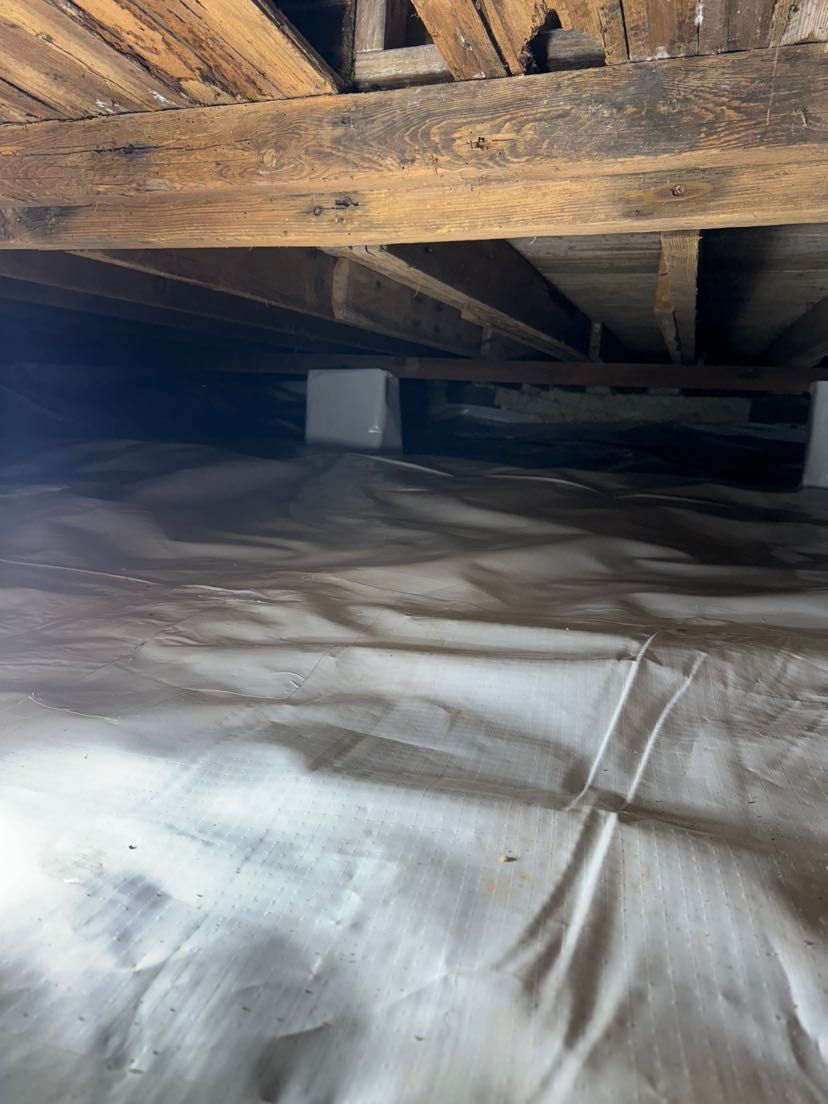 A room with a lot of wooden beams and a white tarp on the floor.