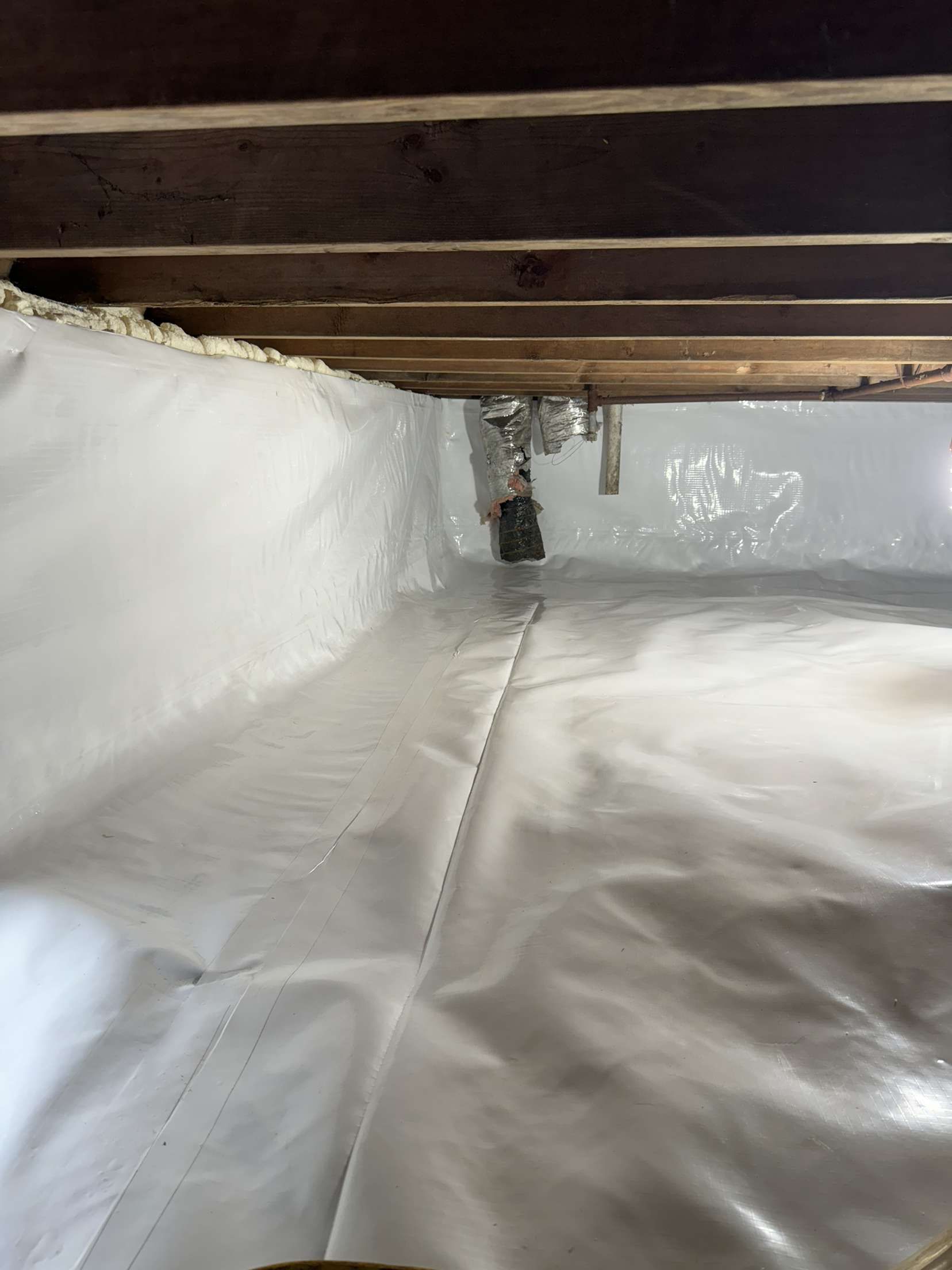 A basement with a white plastic sheet on the floor.