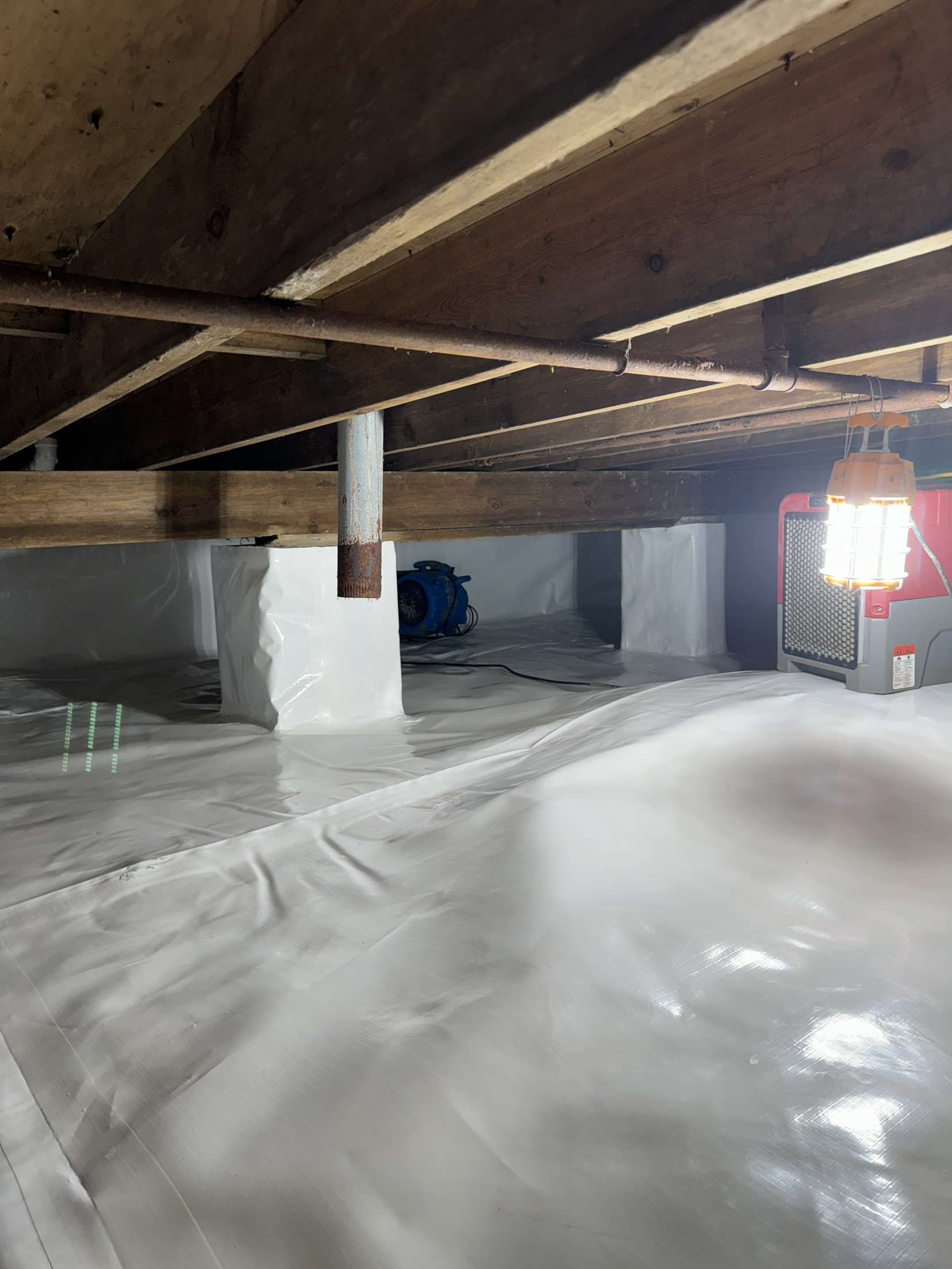 There is a light hanging from the ceiling of a basement.