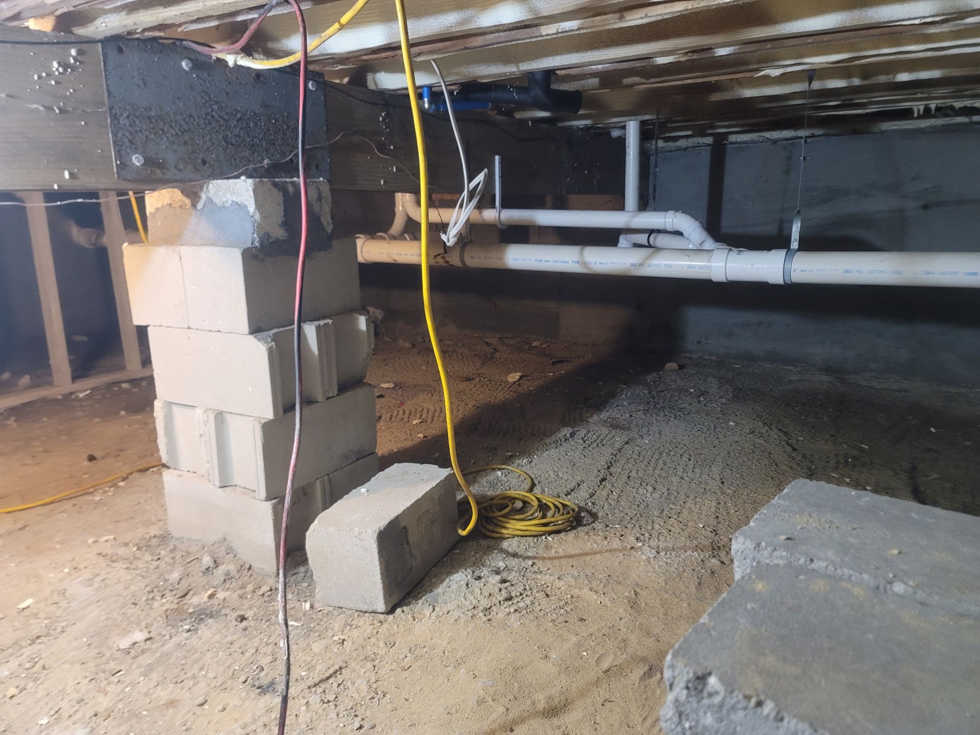 A basement with a stack of bricks and a yellow cord.