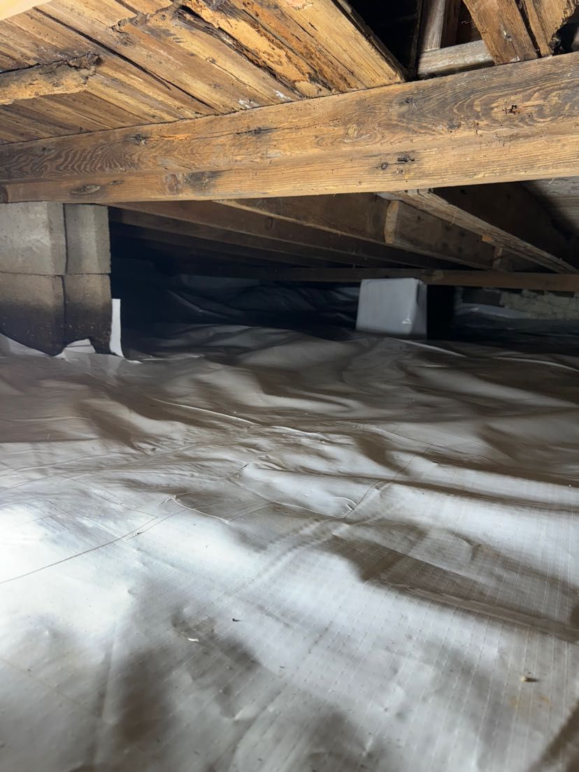 A room with a lot of wooden beams and a white tarp on the floor.