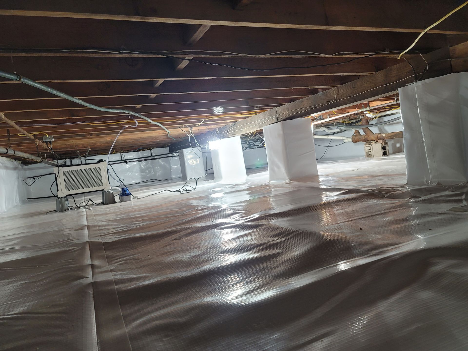 The ceiling of a basement is covered in plastic.