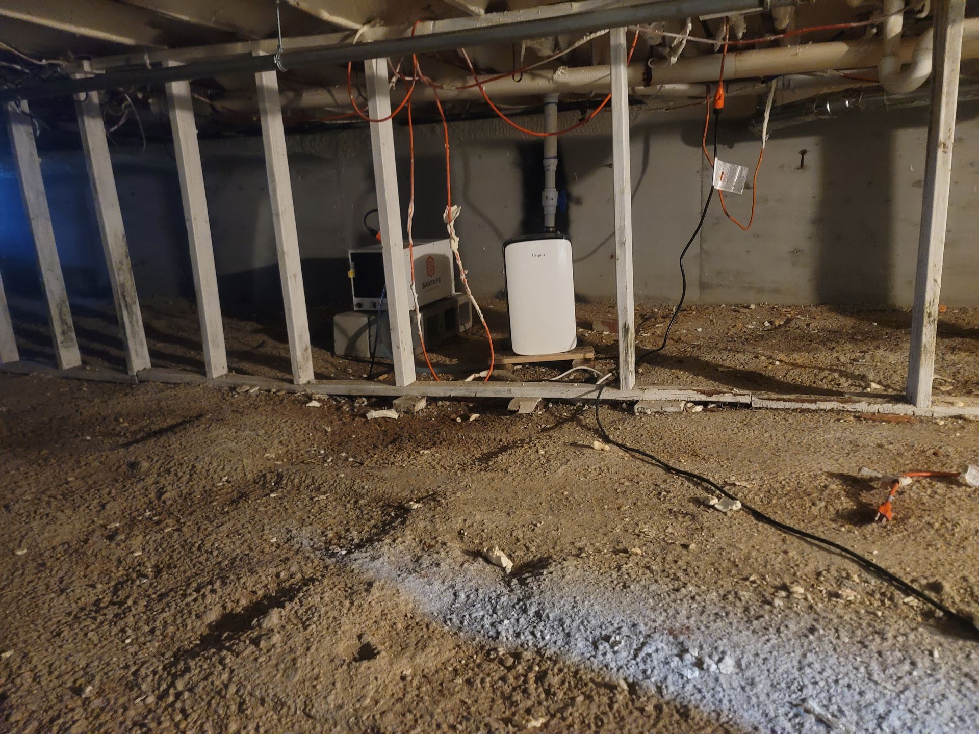 A dirty basement with a ladder hanging from the ceiling.